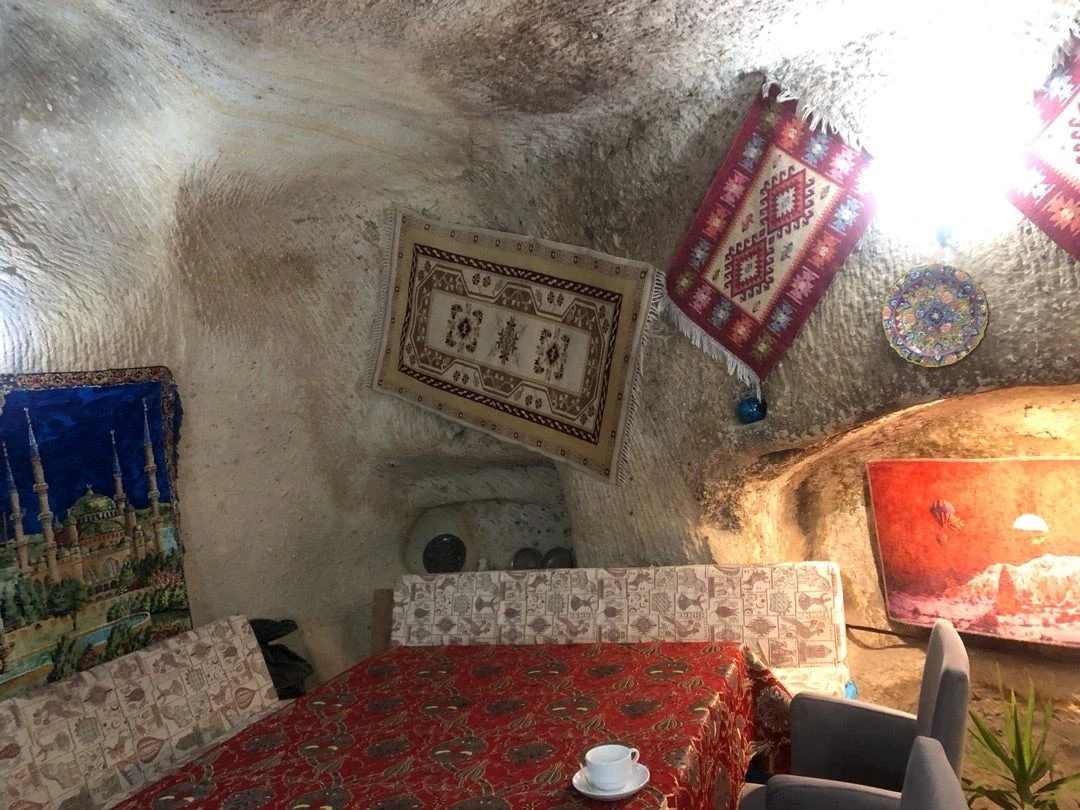 Cave restaurant seating with local textiles at Cavusin Old Turkish House, Çavuşin
