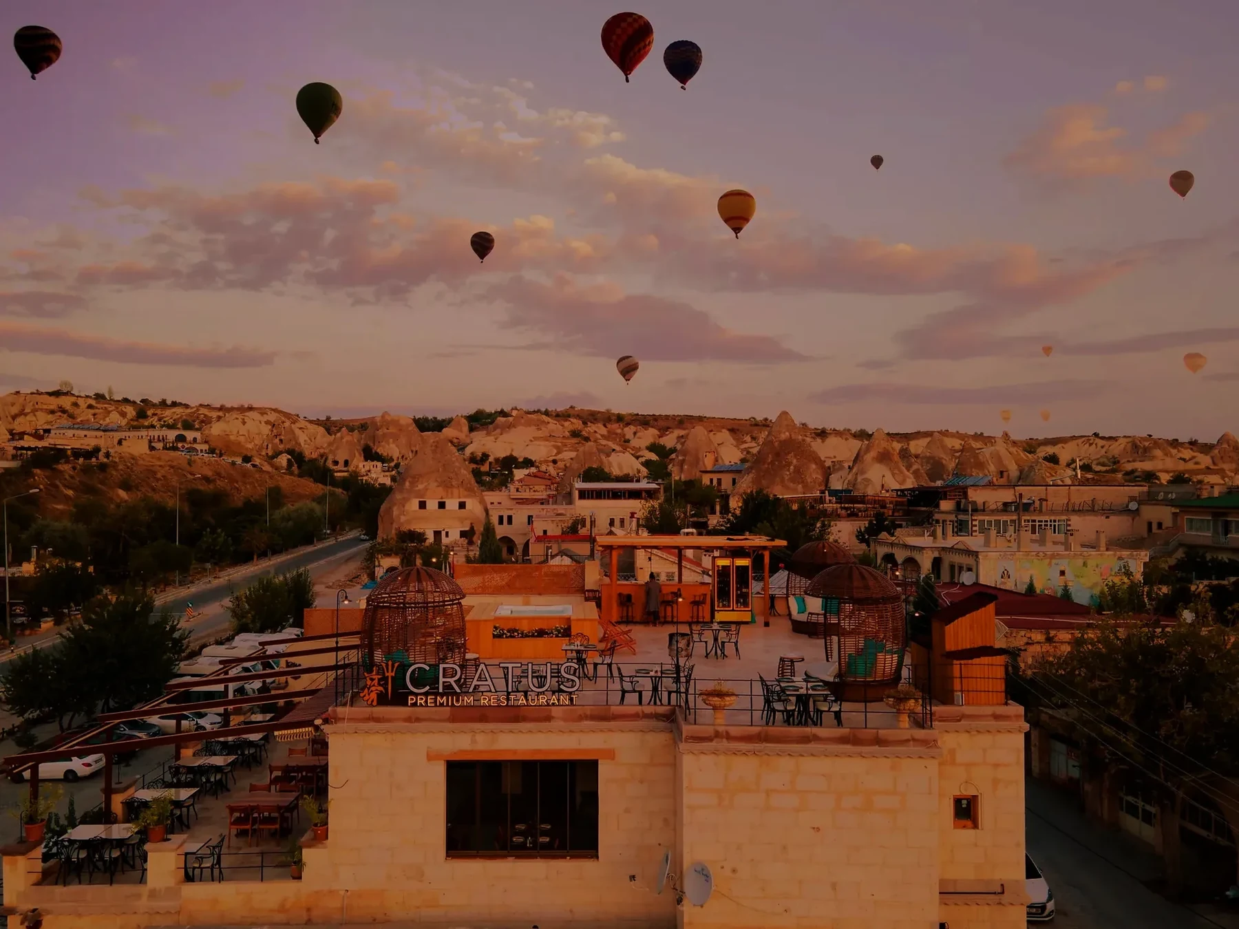 Cratus Premium Restaurant rooftop with hot-air balloons over Göreme