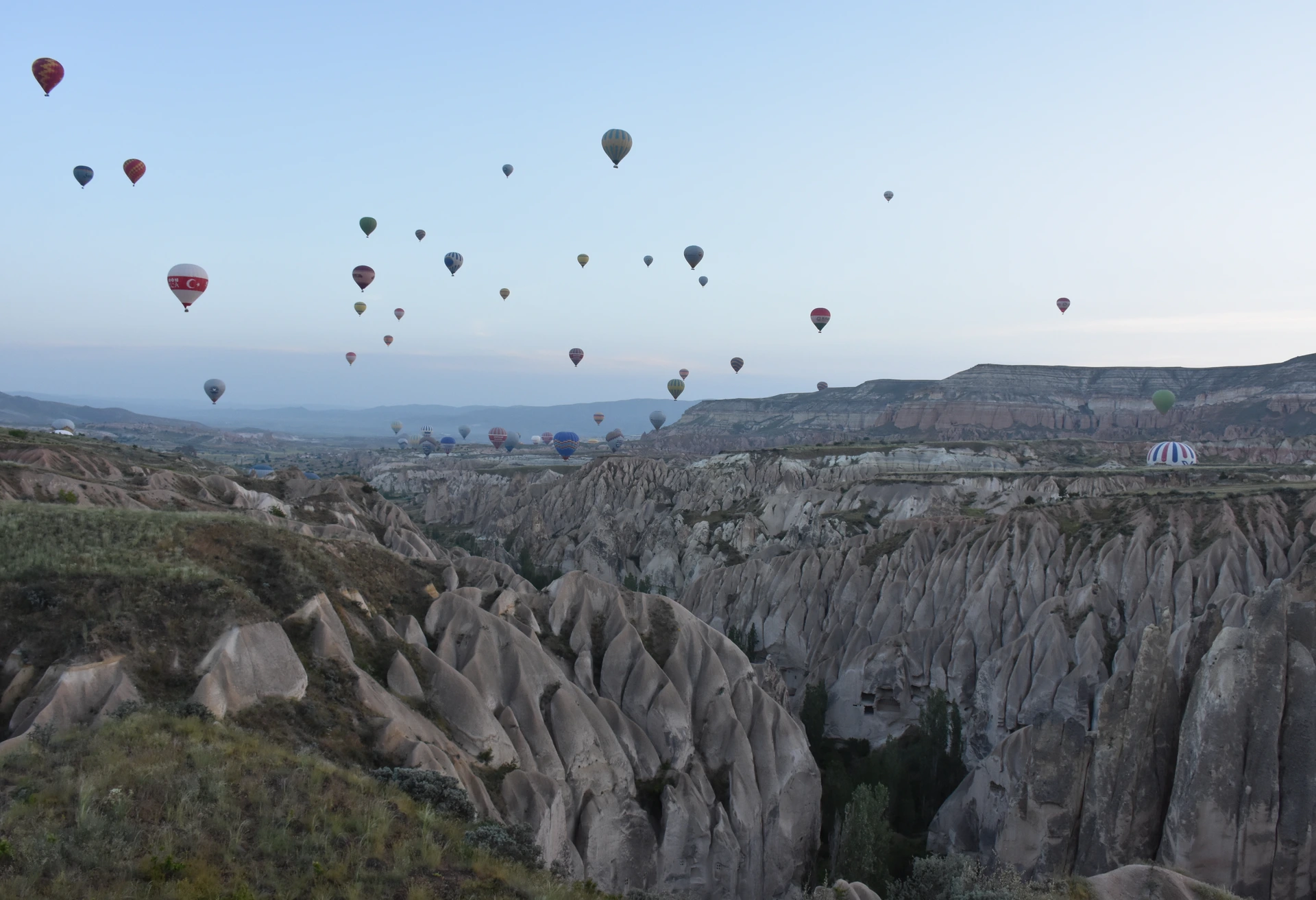 Balloons filling the sky near Göreme at dawn.